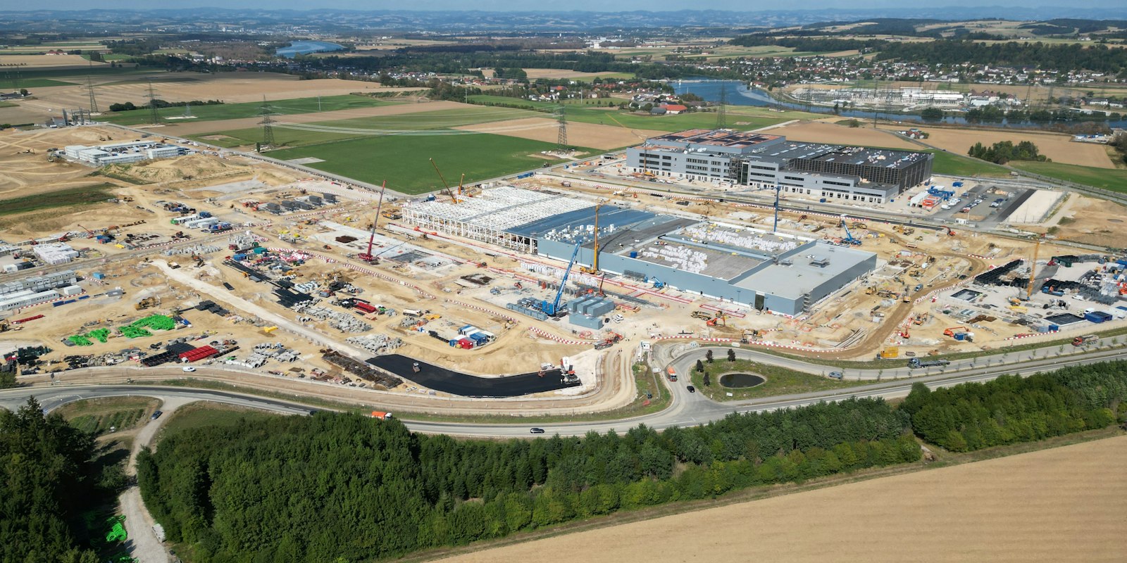 Aerial view of an industrial facility under construction with cranes
